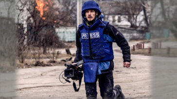 A journalist runs for cover after heavy shelling as Russian troops advance towards the capital, in Irpin, near Kyiv, Ukraine 6 March 2022
